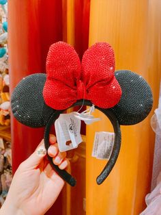 a person holding up a minnie mouse ears headband