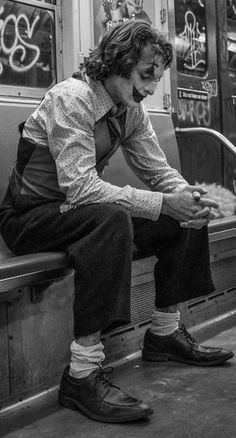 a man sitting on a subway bench with his feet up in the air and wearing socks