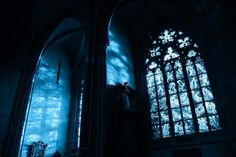 two large stained glass windows in a dark room with blue light coming through the window