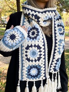 a woman wearing a blue and white crocheted scarf with tassels on it