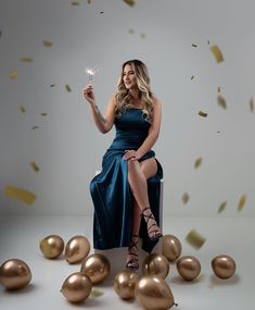 a woman in a blue dress is sitting on a chair and holding a sparkler