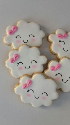 four decorated cookies in the shape of clouds with pink bows on their ears and eyes