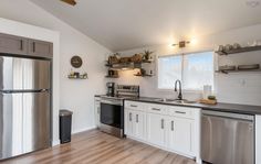 an empty kitchen with stainless steel appliances and wood flooring is pictured in this image