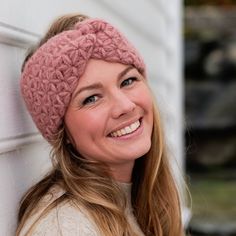 a smiling woman wearing a pink knitted headband