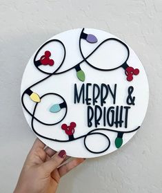 a hand holding up a merry and bright christmas ornament