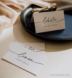 two place cards sitting on top of a black plate