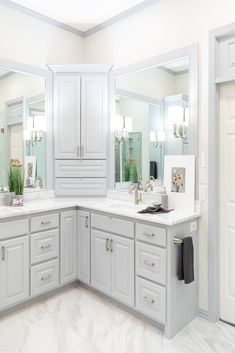 a large bathroom with white cabinets and marble counter tops, along with mirrors on the wall