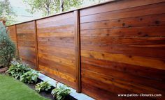 a wooden fence in the middle of a yard with plants growing on top of it