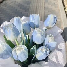 a bouquet of white tulips sitting on the sidewalk