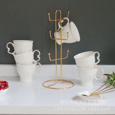 there are cups and saucers on the table with gold wire holders in front of them