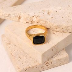 Introducing the Forza Gold Black Gemstone Signet Ring, a dazzling fusion of elegance and modern style. Crafted from high-quality stainless steel with a luxurious 18 karat gold finish, this ring exudes sophistication. The on-trend square-ish design, paired with a sparkling array of gemstone options including black, clear, pink, and green zircons, adds a touch of glamour to any ensemble. Whether you're looking for a statement piece or a stylish gift, the Forza Gold Gemstone Signet Ring is a radian Formal Rectangular Stainless Steel Signet Ring, Formal Stainless Steel Rectangular Signet Ring, Modern Rectangular Stainless Steel Signet Ring, Modern Stainless Steel Rectangular Signet Ring, Minimalist Stainless Steel Rectangular Ring, Modern Gold Plated Signet Ring, Modern Square Ring With Polished Finish, Modern Gold Square Signet Ring, Modern Square Rings For Formal Occasions