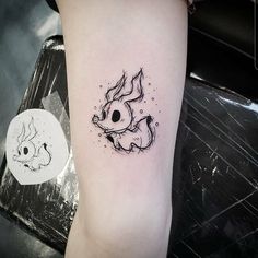 a black and white tattoo on the arm of a woman's left leg, with an image of a fish