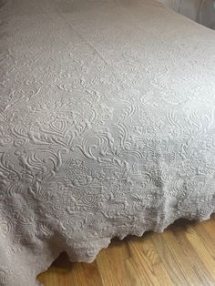 a bed with a white bedspread sitting on top of a hard wood floor