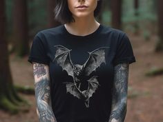 Step into the dark and mysterious realm with this cool bat shirt. This design showcases the nocturnal world, featuring an ominous illustration of two bats that symbolize your inherent connection to the shadows. Whether you embrace dark academia, goth, punk or simply have a fondness for Halloween, this shirt is a perfect addition to your wardrobe.  Bella+Canvas unisex short sleeve tees are made with 100% Airlume combed and ring-spun cotton. * Bella+Canvas manufactures all its products in the US and internationally in humane, no-sweat-shop, sustainable way and is part of the Fair Labor Association as well as Platinum WRAP certified. ● SIZING: * Bella + Canvas 3001 t-shirts are unisex and fit true to size. * Women wanting a slim fit should go down a size. * For an oversized fit, please order Gothic Black T-shirt For Halloween, Edgy Halloween T-shirt For Alternative Fashion, Gothic Distressed Tops For Streetwear, Grunge Tops For Halloween, Alternative Distressed Halloween T-shirt, Gothic Tops For Halloween, Gothic Tops For Halloween And Alternative Fashion, Gothic Short Sleeve T-shirt For Concerts, Gothic Halloween Concert T-shirt