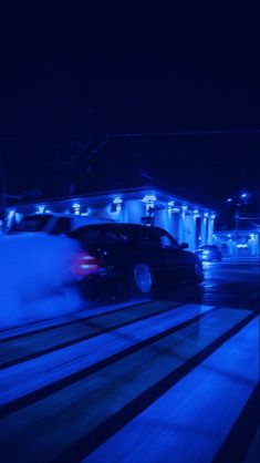 a car driving down the road at night with blue light coming from its exhaust system