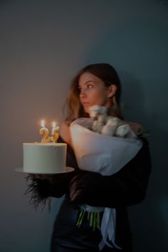 a woman holding a cake with lit candles on it in front of her face and the number twenty