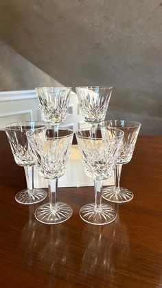 four clear wine glasses sitting on top of a wooden table