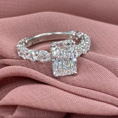 a diamond ring on top of a pink cloth