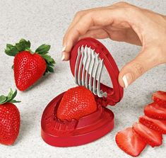 a person cutting strawberries with a fruit slicer