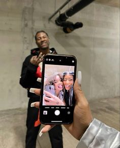 a person holding up a cell phone to take a selfie with two other people in the background