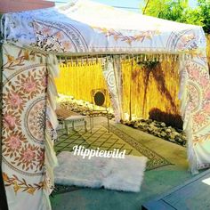 an outdoor gazebo with white curtains and flowers on it