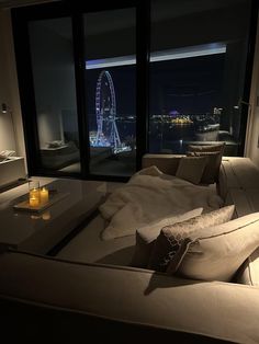 a living room filled with furniture and a large window overlooking the city lights at night