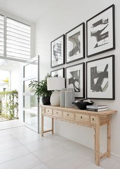 a white room with pictures on the wall and a wooden table in front of it