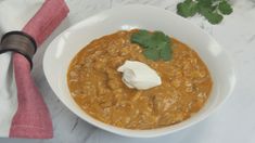 a bowl of chili with sour cream and cilantro garnish on the side