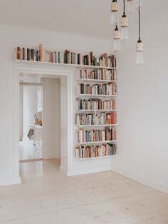 a book shelf filled with lots of books on top of a hard wood floor next to a doorway