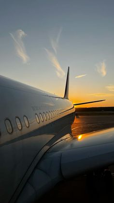 an airplane is sitting on the runway at sunset