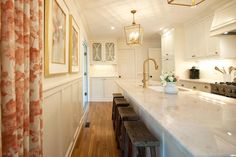 a kitchen with white cabinets and marble counter tops, along with wooden stools in front of the island