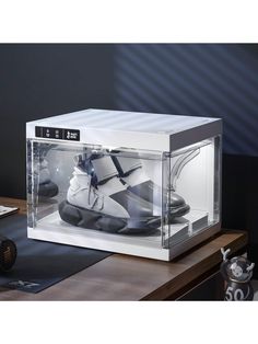 a white box with some black and white shoes in it's display case on a table