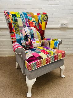 an upholstered chair with patchwork fabric on the back and arms, in front of a white brick wall