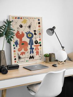 a white desk topped with a laptop computer next to a plant