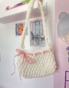 a crocheted purse hanging from a hook on a wall in a girls room