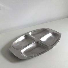 a metal tray with three compartments sitting on top of a white table next to a wall