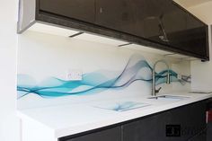 a kitchen with white counter tops and blue waves painted on the wall