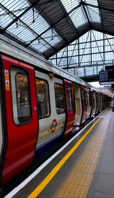 a red and white train pulling into a station next to a loading platform with people on it