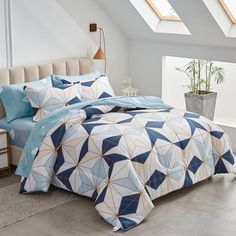 a bed with blue and white bedspreads in a room under a skylight