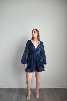 Navy Dress Romper with sparkling belt and long sleeves to dazzle at any formal event. Featuring an adjustable belt and a plunging v-neckline, you can elevate your look with sky-high heels or simply make it a more relaxed ensemble for at-home soirées. Crafted from a lightweight Polyester, this Navy Dress Romper is the epitome of grace and sophistication. Size guide: The First Model is 5'6" and wearing size Small. The Second model is wearing a size small Cocktail V-neck Belted Mini Dress, Glamorous V-neck Mini Dress For Formal Occasions, Elegant Belted Mini Dress For Party, V-neck Mini Dress For Date Night Evening, Glamorous Belted Dress For Formal Occasion, Glamorous Belted Party Dress, Glamorous Belted Formal Dresses, Glamorous Belted Evening Dress, Glamorous Formal Belted Dress