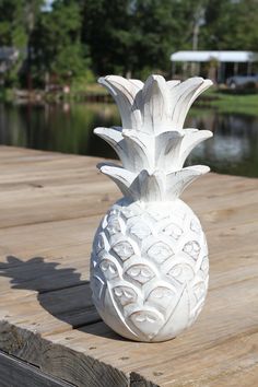 a white pineapple vase sitting on top of a wooden dock