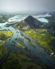 an aerial view of a river running through a valley with mountains in the back ground