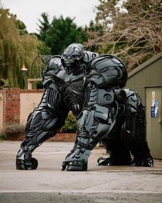 a giant robot statue sitting in the middle of a parking lot next to a building