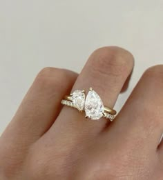 a woman's hand with three pear shaped diamonds on top of her wedding ring