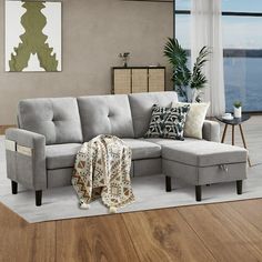 a living room with a sectional couch and pillows on the floor next to a large window