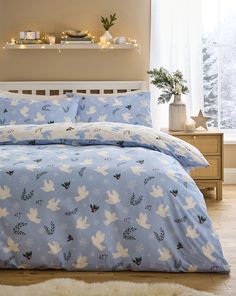 a bed with doves and holly on it in a bedroom next to a window