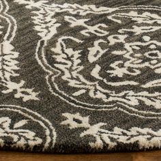 an area rug with white and gray designs on it, sitting on a wooden floor