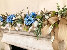 a fireplace mantel decorated with blue flowers and greenery