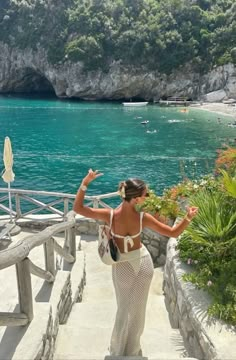 a woman is walking down some stairs near the water