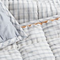 an unmade bed with blue and white checkered sheets